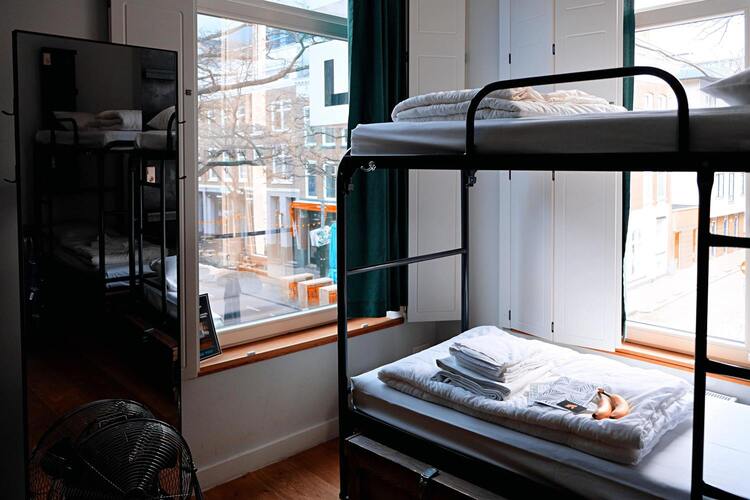 petite chambre avec lits superposés et deux fenêtres sur rue